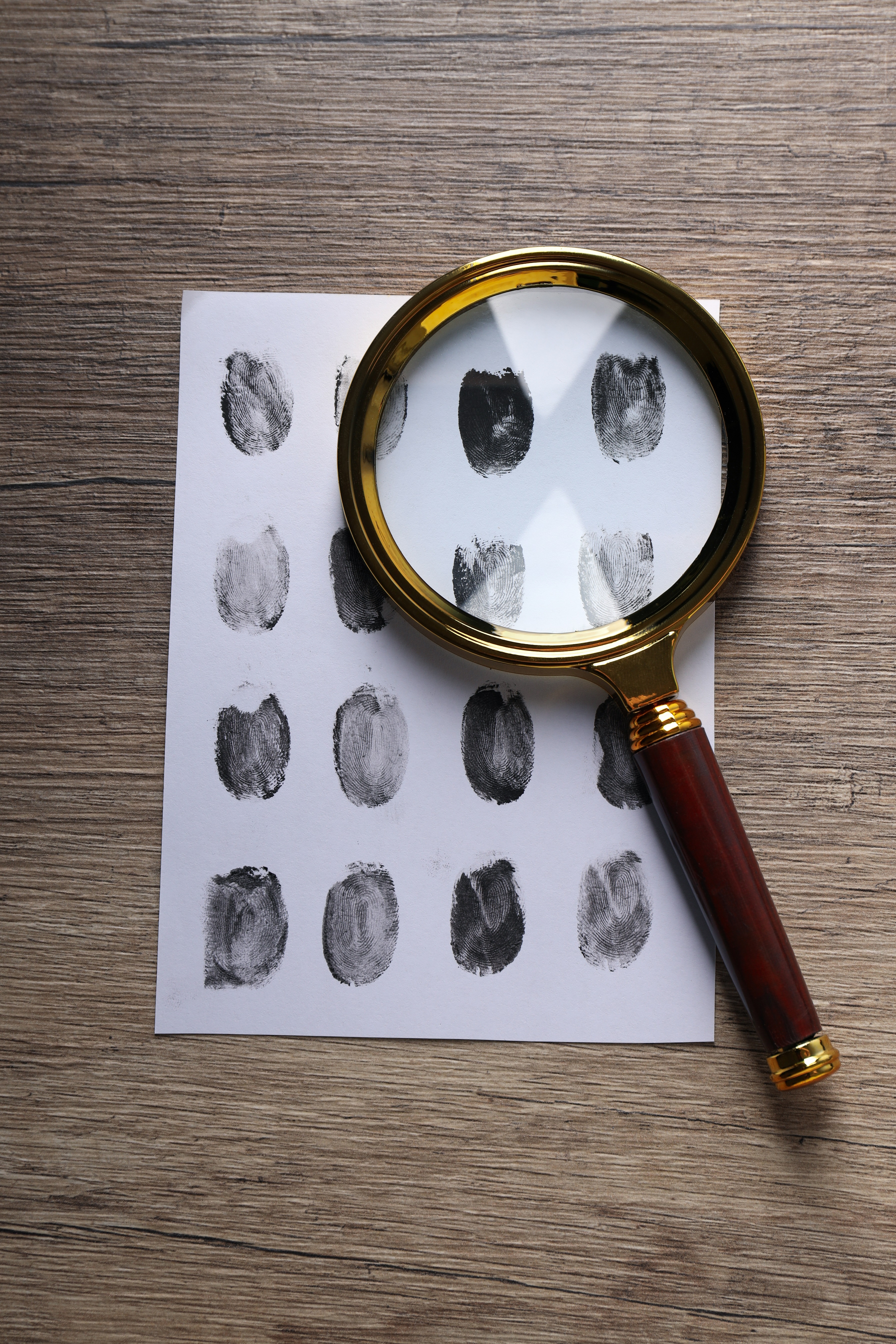 Magnifying glass with envelope with fingerprints on wooden background